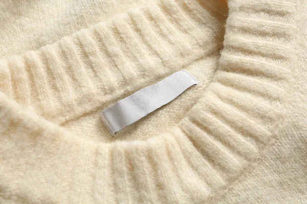 Blank clothing label on white cashmere sweater, top view