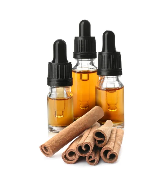 Bottles Natural Essential Oil Dry Cinnamon Sticks White Background — стоковое фото