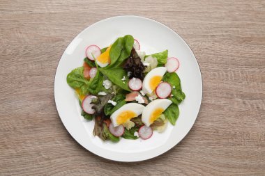 Haşlanmış yumurtalı lezzetli salata, ahşap masada turp ve peynir.