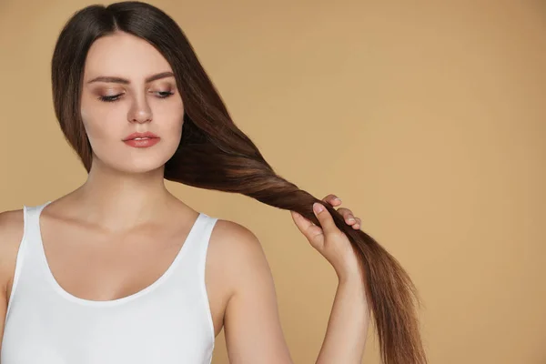 Young woman with strong healthy hair on beige background