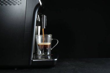 Gri masada, siyah arka planda modern espresso makinesiyle kahve yapmak. Metin için boşluk