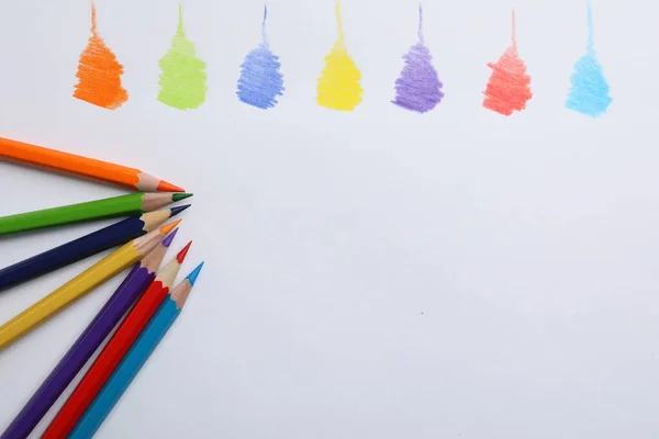 Colorful pencils with swatches on white background, top view