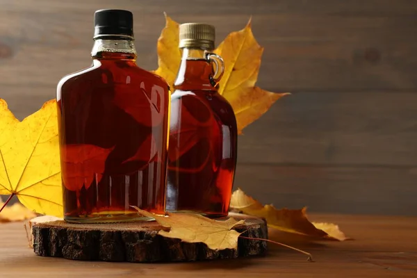 Bottles Tasty Maple Syrup Dry Leaves Wooden Table Space Text — Stock Photo, Image