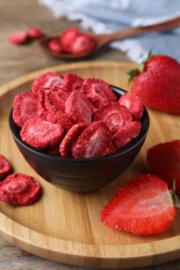 Dondurulmuş kuru ve taze çilekler ahşap masada, yakın plan.