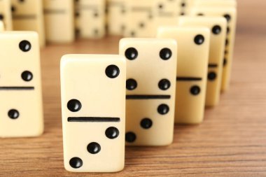 White domino tiles with black pips on wooden table, closeup