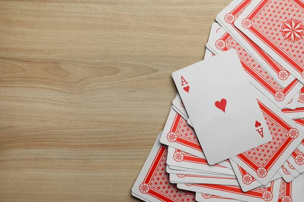 Deck of playing cards on wooden table, flat lay. Space for text