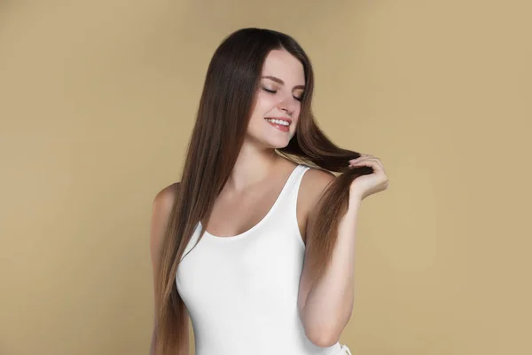 Young woman with strong healthy hair on beige background