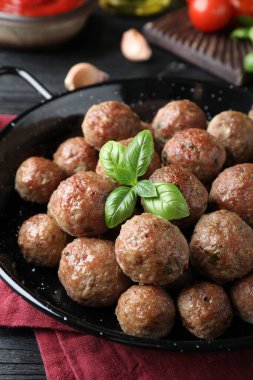 Lezzetli pişmiş köfteler, siyah ahşap masada fesleğen, yakın plan.