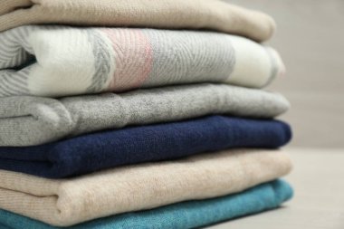 Tahta masanın üzerine yığılmış kaşmir giysiler, yakın plan.