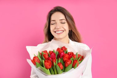 Pembe arka planda kırmızı lale buketi olan mutlu kadın. 8 Mart kutlamaları