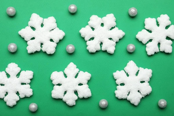 Beautiful decorative snowflakes and decor on green background, flat lay