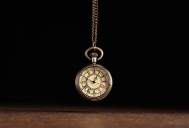 Stylish pendulum above wooden table on black background. Hypnotherapy session