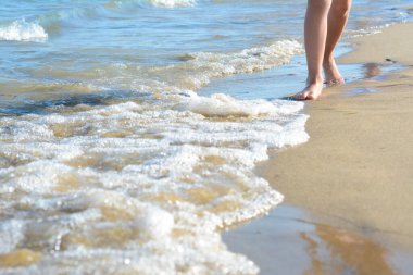 Çocuk deniz kıyısında yürüyor, bacaklarına yakın. Metin için boşluk