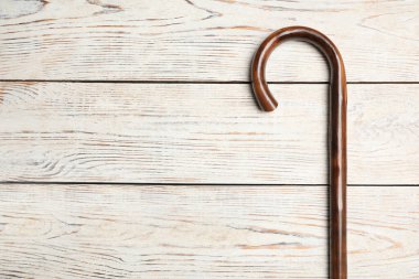 Walking cane on white wooden background, top view. Space for text