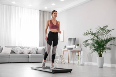 Spor kadın evde yürüyüş bandında antrenman yapıyor.