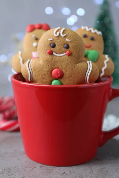 Gingerbread men in cup on light table against blurred lights, closeup