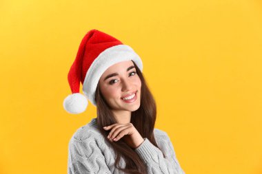 Sarı arka planda Noel Baba şapkası takan güzel kadın.
