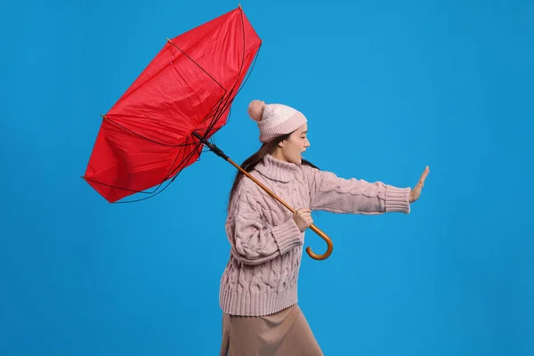 Junge Frau Mit Regenschirm Windböe Auf Hellblauem Hintergrund Gefangen — Stockfoto