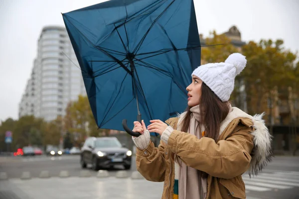 青い傘を持った女性が路上で風に吹かれて — ストック写真