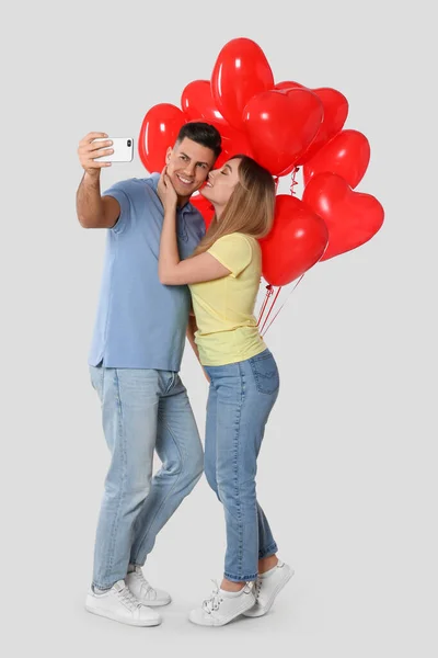 Urocza Para Balonami Kształcie Serca Robi Selfie Jasnoszarym Tle Walentynki — Zdjęcie stockowe