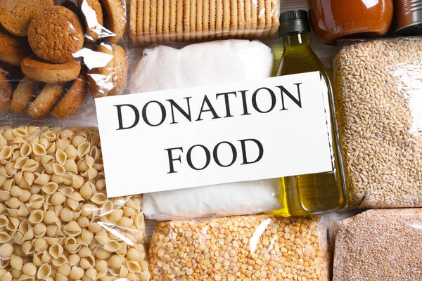 Card with words Donation Food and different products on table, flat lay