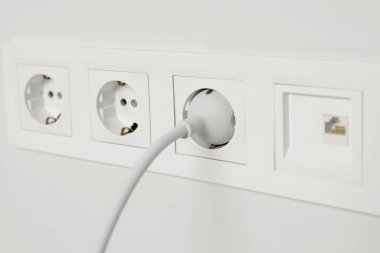 Elektrik prizleri beyaz duvara takılı, yakın plan. Elektrik arzı