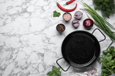Flat lay composition with frying pan and fresh products on white marble table, space for text