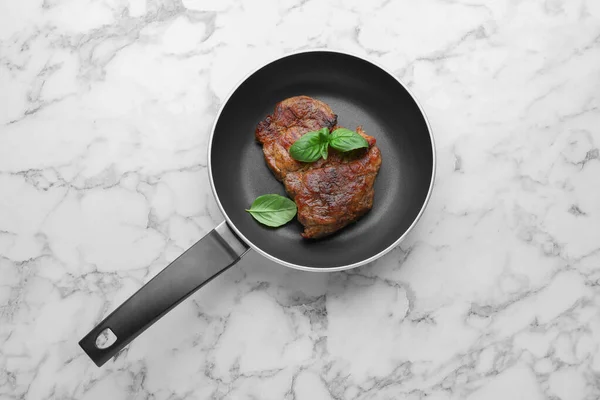 白い大理石のテーブルの上に鍋でおいしい揚げステーキ トップビュー — ストック写真