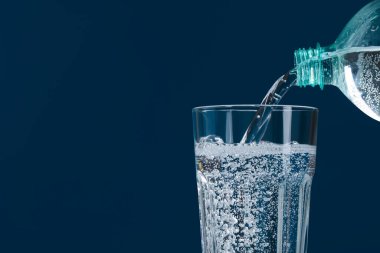 Mavi arka planda şişeden cama soda dökmek, yakın plan. Metin için boşluk