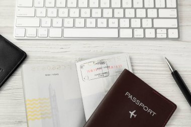 Moldova, Ceadir-Lunga - 13 Haziran 2022: Vize damgalı pasaportlar, bilgisayar klavyesi ve beyaz ahşap masa üzerindeki kalem, düz konum