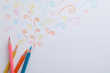 Beyaz arkaplanda soyut çizimler ve renkli kalemler, üst görünüm