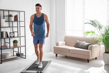 Spor adam evde yürüyüş bandında antrenman yapıyor.