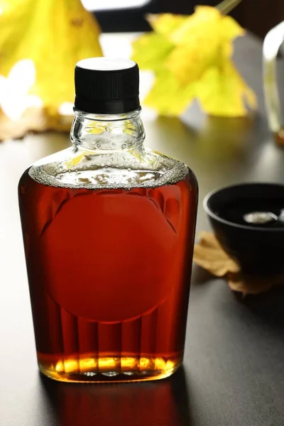 Bottle of tasty maple syrup on grey table