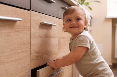 Little child exploring drawer indoors. Dangerous situation