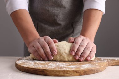 Gri duvarın yanındaki masada hamur yoğuran adam, yakın plan.