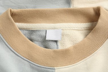 Blank clothing label on stylish sweater, top view