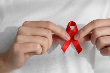 Kırmızı farkındalık kurdelesi tutan kadın, yakın plan. Dünya AIDS Hastalıkları Günü