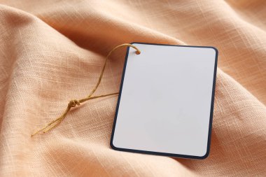 Soluk turuncu kumaş üzerine yazı için alanı olan karton etiket, yakın plan