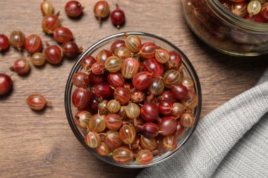 Many fresh ripe gooseberries on wooden table, flat lay