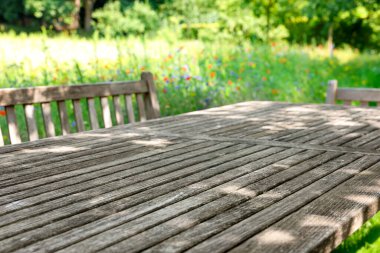 Empty wooden table with bench on sunny day in garden