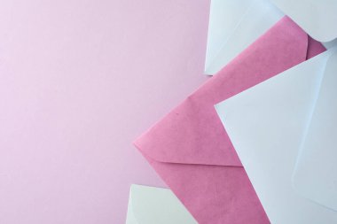 Pembe arka planda renkli zarflar, düz yatış. Metin için boşluk