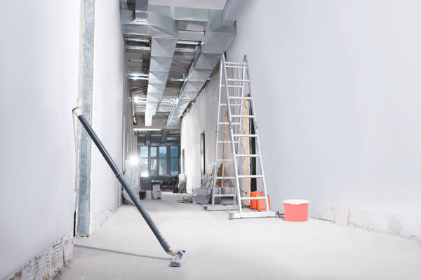 Metal ladder and building materials in hall prepared for renovation