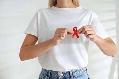 Kırmızı farkındalık kurdelesini arka planda tutan kadın, yakın plan. Dünya AIDS Hastalıkları Günü