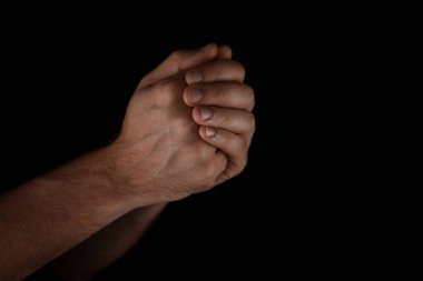 Siyah arkaplan karşısında dua eden adam, yakın plan görünümü