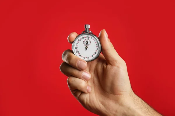 Man holding vintage timer on red background, closeup