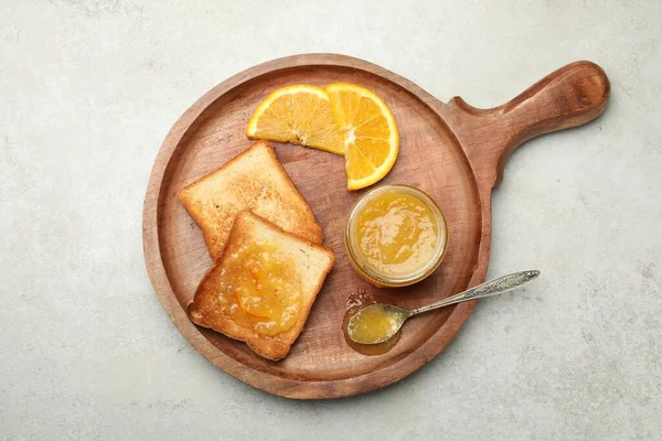 Delicious toasts with orange marmalade on light grey table, top view