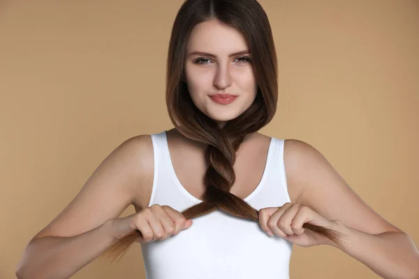 Young woman with strong healthy hair on beige background