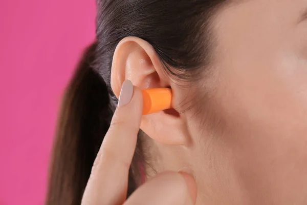 Junge Frau Steckt Schaumstoff Ohrenstöpsel Auf Rosa Hintergrund Nahaufnahme — Stockfoto