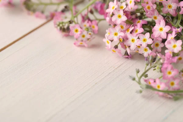 Beautiful Forget-me-not flowers on white wooden table, closeup. Space for text