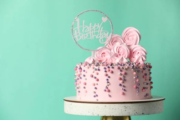 Beautifully decorated birthday cake on stand against turquoise background, space for text